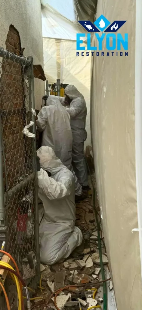 Asbestos removal specialists in protective suits working in Denver, Colorado's confined space