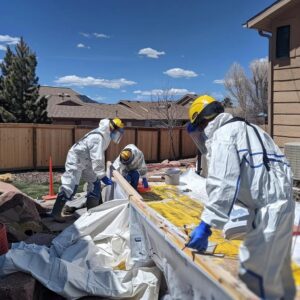 Asbestos abatement team in Denver wearing protective gear while working on a residential property