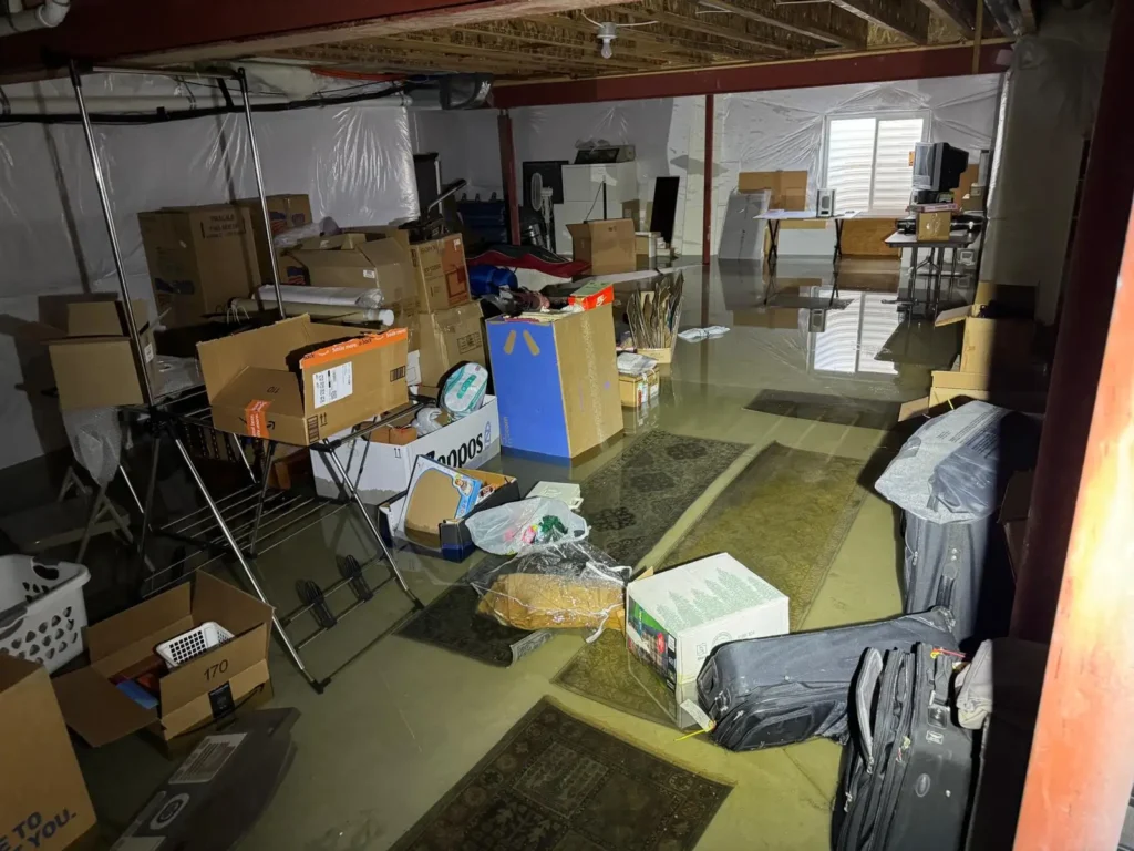 Emergency water damage restoration technician documenting frozen pipe burst damage in Denver basement for insurance claim approval with professional moisture detection equipment